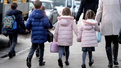 Parents walking their children to school