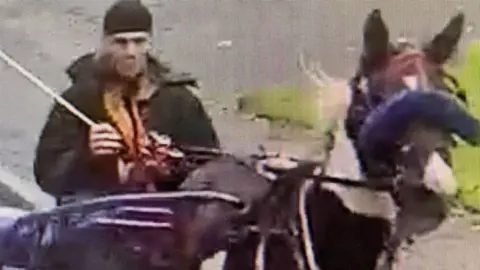 CCTV image of person wearing black riding a horse 