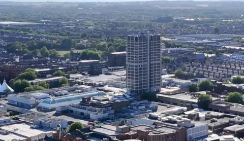 An aerial shot of Swindon with large buildings, parked cars and a cloudy sky