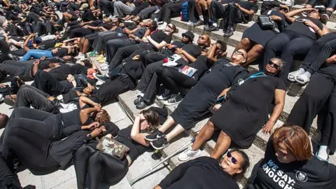 Gallo via Getty Images Students and staff members at South Africa's University of Cape Town are seen wearing black attire as they take part in a silent protest
