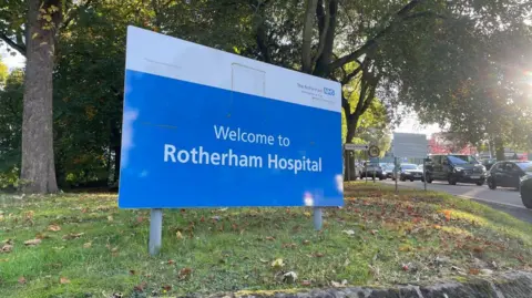 BBC A Rotherham Hospital sign on a grassy bank.