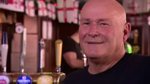 Image of a smiling, bald man wearing a black shirt