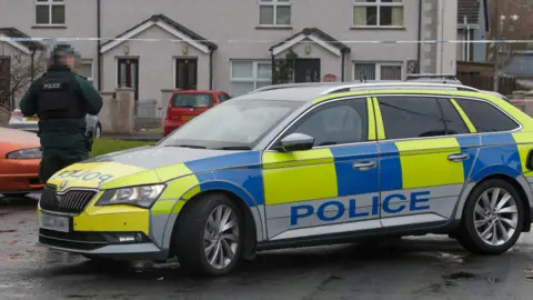 Pacemaker Police officer in uniform and yellow and blue police vehicle at Breezemount Close in Conlig