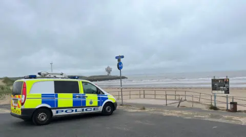 BBC/Leanne Harper Police van parked at beach as emergency services search for missing teenager 