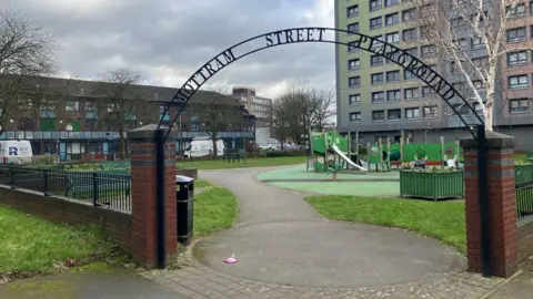 Photograph of the children's playground on the Mottram Street estate in Stockport. In the background is social housing owned by Stockport Homes.