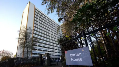 PA Barton House, a social housing tower block in Bristol with trees and a gate in front of it