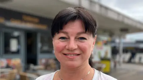 Jon Wright/BBC Ms Revkova stands outside as she smiles at the camera She wears a white top. 