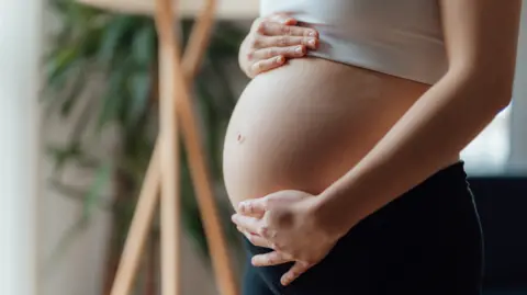 Getty Images Side view close-up of pregnant woman touching her belly.