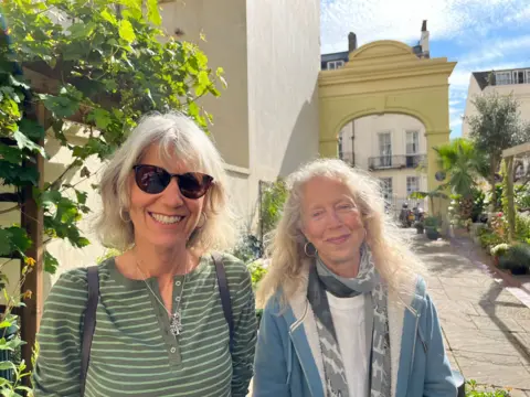 George Carden / BBC Jenny Granville and her sister Judy standing in the garden with plants around them