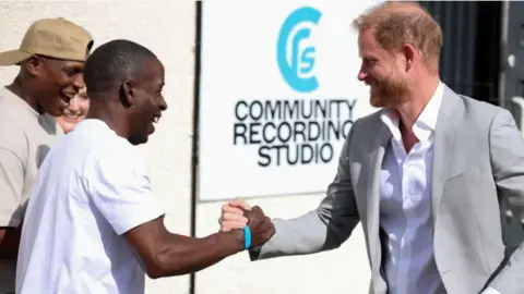 Reuters Trevor Rose and Prince Harry smile as they clasp each other's hands outside the Community Recording Studio