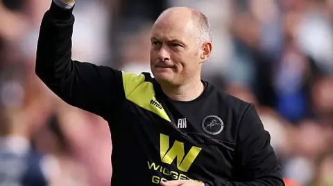 Alex Neil raises his fist to salute the Millwall fans