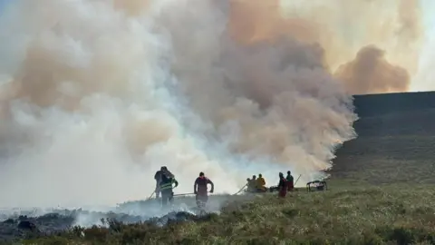 RSPB Scotland people battle a smoking wildfire on a field 
