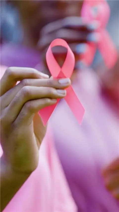 A person holding up a pink breast cancer ribbon