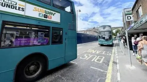 Two buses driving down a street 
