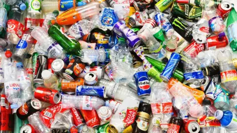 A colourful image of a large and varied collection of bottles and cans, hopefully ready for recycling - they include a range of recognisable brands of both soft and alcoholic drinks as well as water and sports drinks.