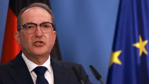 EPA An older man with a receding hairline and glasses wears a dark suit and tie.