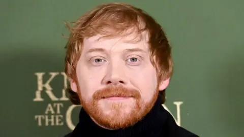 Getty Images Rupert Grint pictured with a green background.