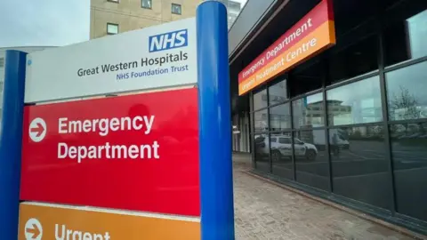 A general view of the outside of Swindon's Great Western Hospital. The picture shows the entrance to the emergency department, with two signs visible. 