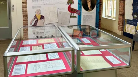 National Trust Two large table top glass display cases showing a number of documents, housed within a heritage building.
