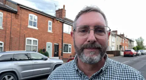 Steven Moss, pictured in Alport Terrace wearing a chequered green shirt and glasses 