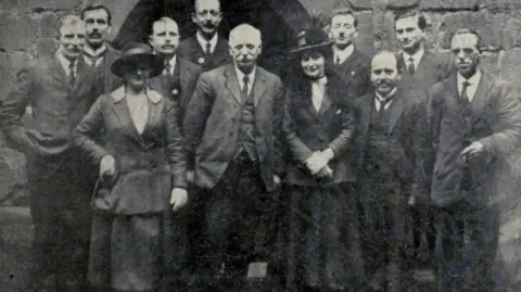 Culture Coventry Trust/Coventry Archives A black and white photograph and a group of men and women stood in front of  a building.