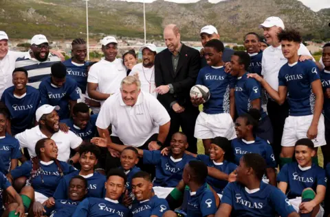 PA Media The Prince of Wales poses for a photograph with the local school children after taking part in their rugby coaching session during a visit to Ocean View Secondary School in Cape Town, South Africa.