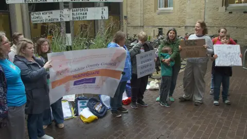 Campaigners made up of women and children with placards gather outside County Hall.