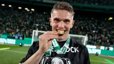 Viktor Gyokeres bites his title winner's medal