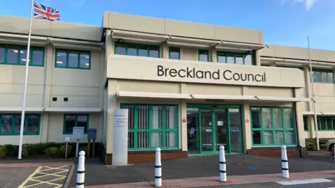 LDRS A light grey, two-storey office building with the words "Breckland Council" over the front main entrance.