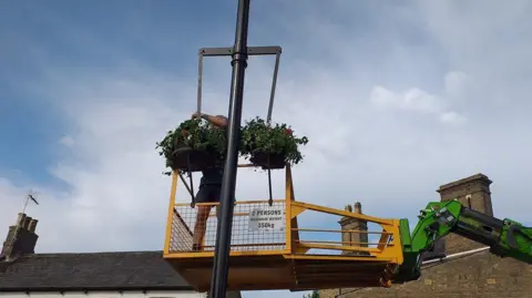 Chatteris in Bloom A man putting hanging baskets on a lamppost 