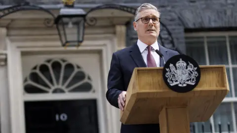 EPA/Shutterstock A suited speaker, Sir Keir Starmer, delivers a statement from a lectern outside Number 10 Downing Street.
