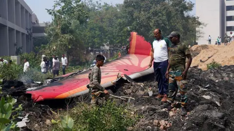 Getty Images Wreckage from a plane can be seen in a residential area of India. Several people are pictured near part of the plane