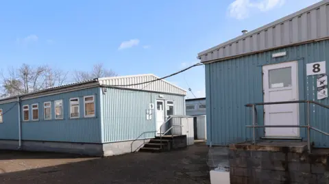 Two blue buildings made out of corrugated metal 