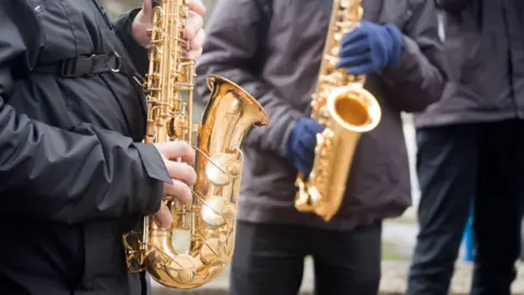 Getty Images Two young men playing saxophone outdoors, marching band in a traditional celebration