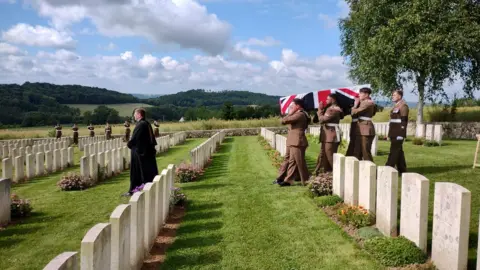 MoD Members of the army bear a coffin draped in the Union Flag through a graveyard, led by a vicar