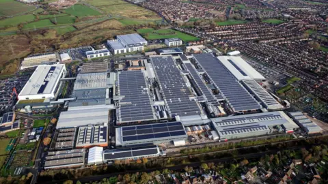 Bentley An aerial view of a large car factory with a number of factory and office buildings clustered together. Residential estates and fields can be seen surrounding the site.