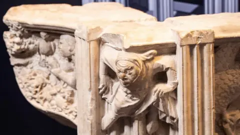 Danny Lawson/PA A fragment of a medieval shrine dedicated to York’s patron saint, St William. A large stone piece of a column, with a stone figurehead of a crouching figure.