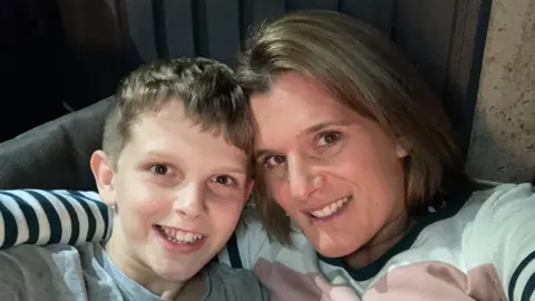 PA Ellen Roome and her son Jools. She has brown hair and eyes and is wearing a stripey top. Jools has a grey t-shirt on and brown hair.