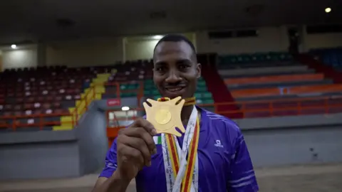 A man holding a medal in a sports hall