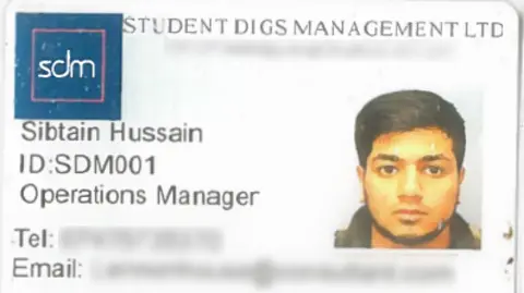 An identification card for an organisation called STUDENT DIGS MANAGEMENT LTD. In the top-left corner, there is a blue square logo containing the letters “sdm” in white text. Beneath the logo and printed to the left side of the card are the following details: Name: Sibtain Hussain ID: SDM001 Position: Operations Manager Below these lines, there are fields for a telephone number and email address, both of which are blurred. On the right side of the card, there is a small portrait area where a person is pictured.