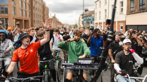 @shotbygenaro DJ Dom Whiting speaking into a microphone leads hundreds of riders through Nottingham streets