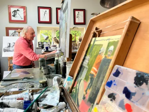 Roy works on a painting of Ratcliffe-on-Soar power station at home in his studio