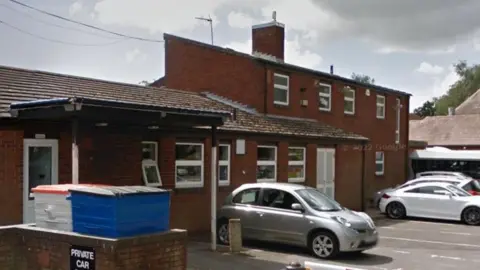 Google Exterior view of the brick-built community centre with cars parked outside