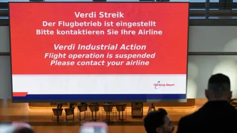 Reuters A screen displays information about a strike at Hamburg airport, during an unexpected early strike affecting passengers, one day before a 24-hour strike at German airports called by the German trade union Verdi over a wage dispute, in Hamburg, Germany March 9, 2025.