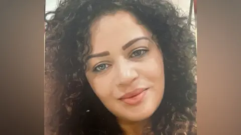 Family Leanne Byrne looks at the camera with curly brown long hair and brown/green eyes. She has a slight smile on her face and her image fills the picture.