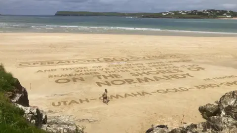 Harry Maddox On of the artists walking away from the completed script in the sand