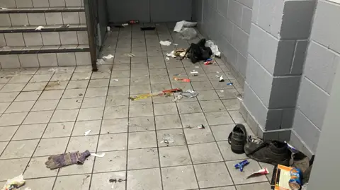 The inside of a building showing a stairwell littered with rubbish.