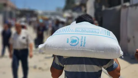 Getty Images A Palestinian man carries a sack of flour.
