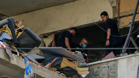 People inspect the damage inside a building following an Israeli strike on the southern suburbs of Beirut.
