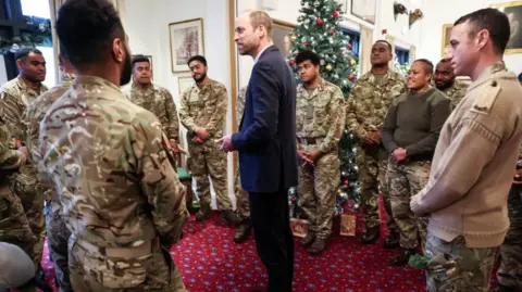 Richard Pohle/The Times/PA Wire Prince William with a circle of Fijian soldiers in uniform surrounding him in a large room with a Christmas tree in the background